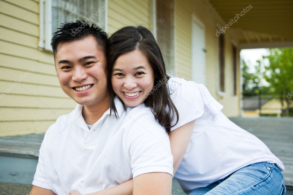 Asian couple in front of their house