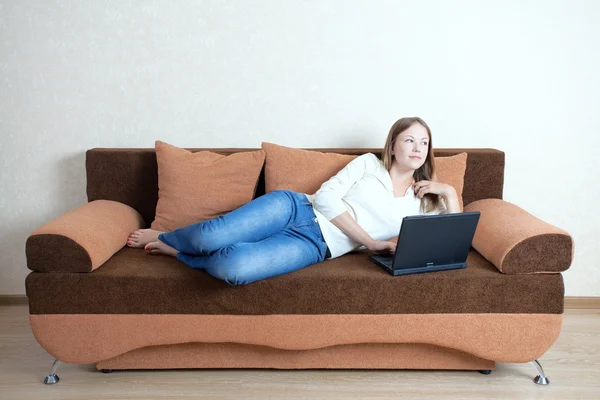 Жінка з ноутбуком на дивані Стокове Фото