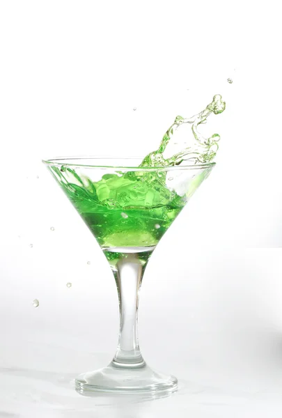 Green martini cocktail splashing into glass