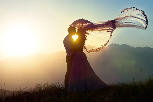 Ženich a nevěsta kiss v horách proti poklesu. Stock Obrázky