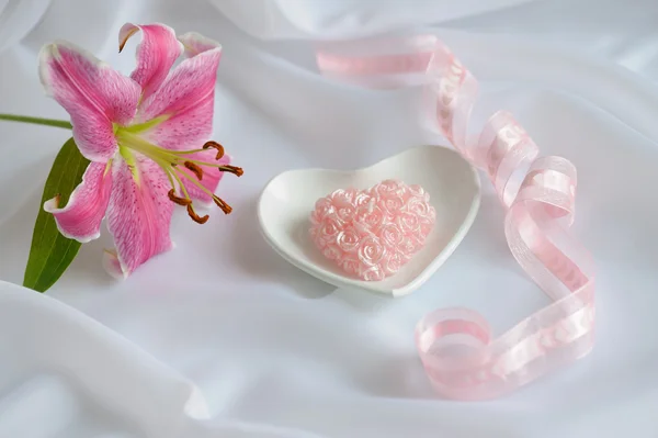 Svíčka Tvaru Srdce Růžové Růže Růžovými Lily Bílé Hedvábné Pozadí — Stock fotografie