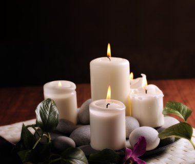 Spa still life with burn white candles and pebbles on dark background clipart