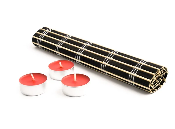 Esterilla Bambú Negra Enrollada Con Tres Pequeñas Velas Rojas Sobre Fotos de stock libres de derechos