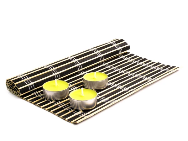 Siyah bambu hasır ve üç sarı mum — Stok fotoğraf