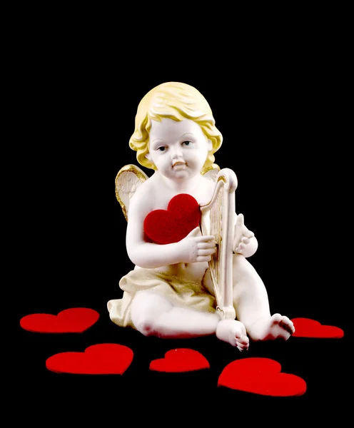 Ceramic cupid with felt heart on black — Stock Photo, Image