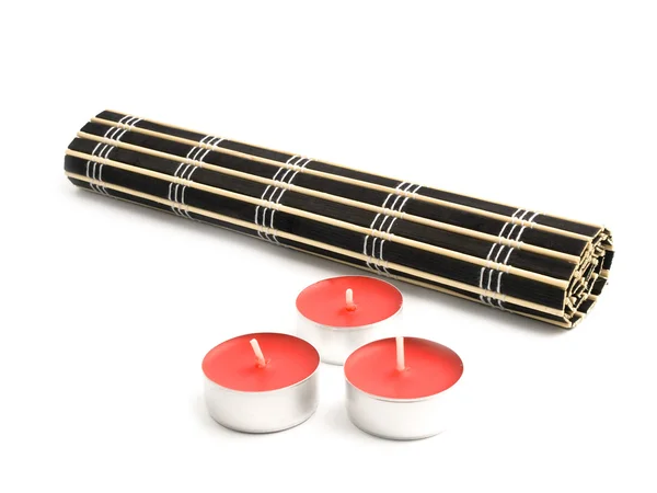 Walcowane bambus czarny mat i trzy czerwone świece Zdjęcie Stockowe