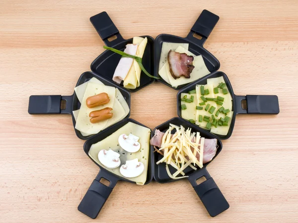 Raclettepfannen mit Essen, ideal zum Feiern lizenzfreie Stockfotos