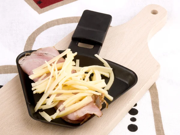Raclette pan with cheese and ham - party food — Stock Photo, Image