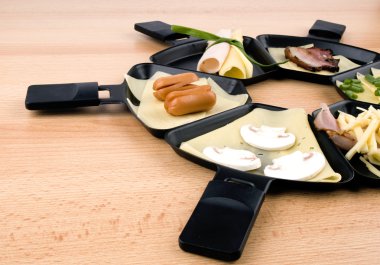 Raclette pans with food, ideal for party clipart