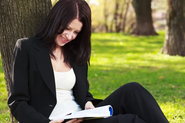 De zakenvrouw zittend op een gras, lezen van een boek — Stockfoto