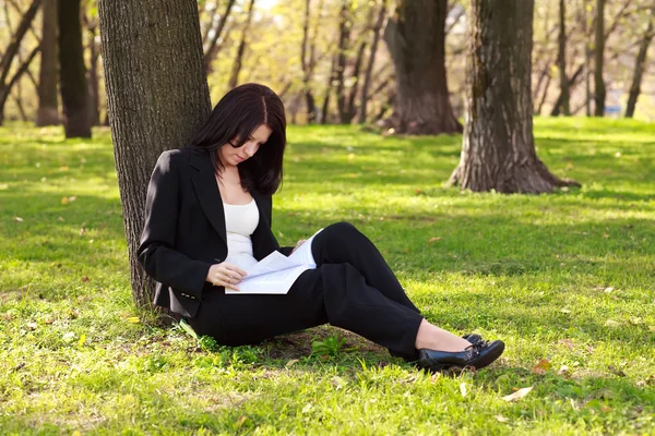La femme d'affaires assise sur une herbe, lisant un livre — Photo