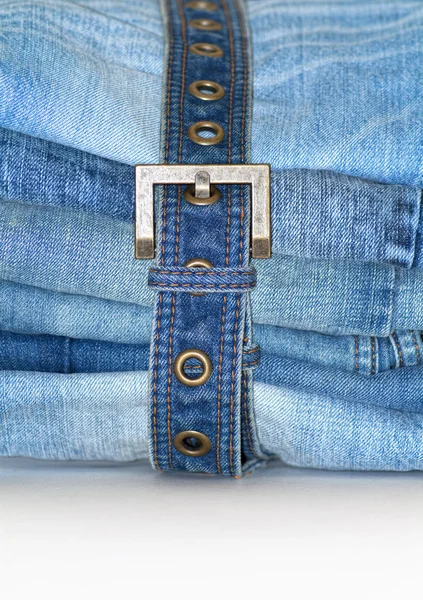 Stack of folded blue jeans with jean belt — Stock Photo, Image