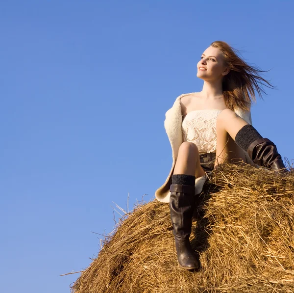 Vacker kvinna placering på höstacken under blå himmel — Stockfoto