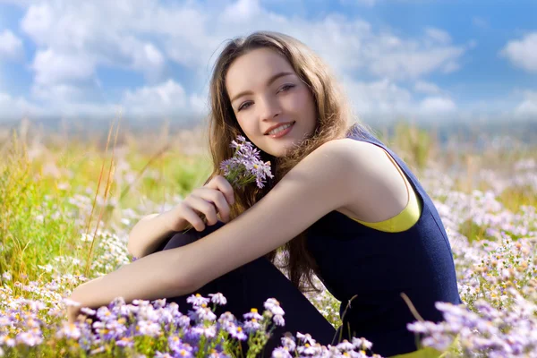 Šťastný mladý teenager na louce s květinami — Stock fotografie