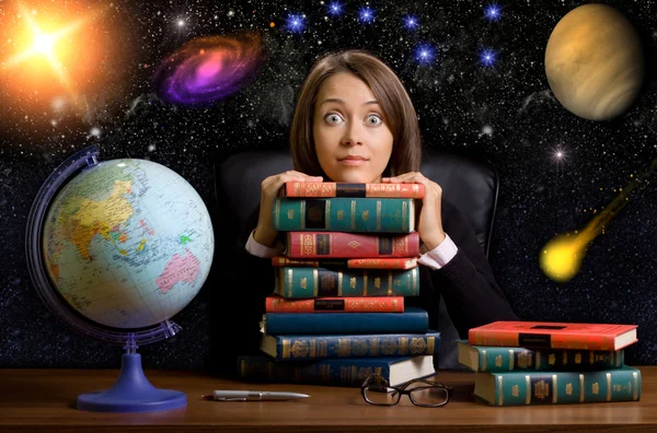 Giovane donna con molti libri alla scrivania su sfondo spazio — Foto Stock