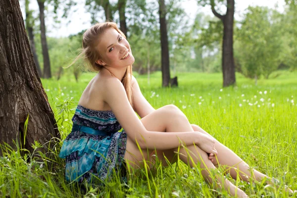 美丽的年轻女孩，在蓝色的裙子在草地上 — 图库照片