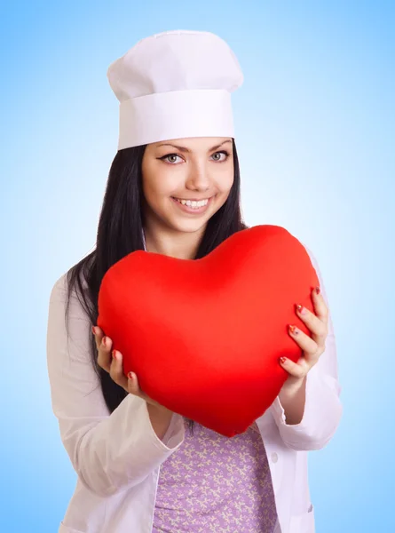 Женщина-врач держит сердце на синем фоне — стоковое фото