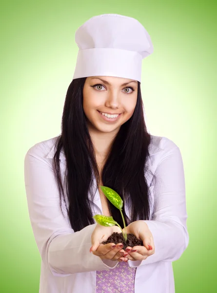 Retrato de mulher sorridente em uniforme branco, segurando a planta dentro dela — Fotografia de Stock