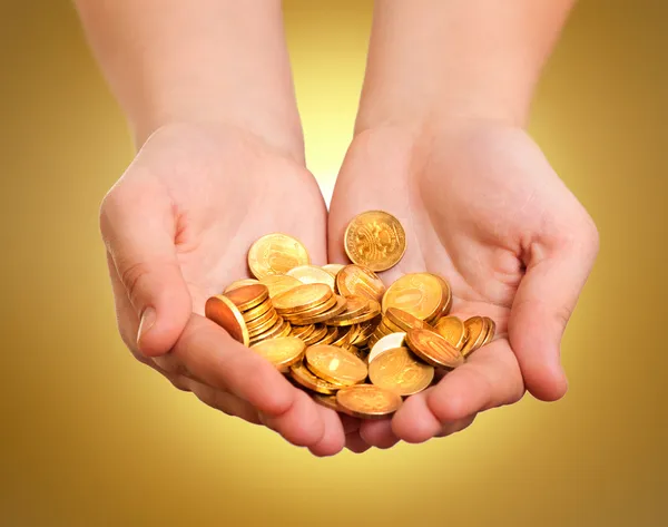 Manos con monedas de oro sobre fondo amarillo Imagen de stock