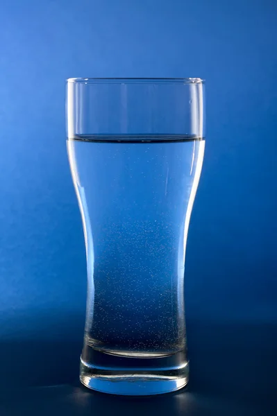 Água pura em vidro em fundo azul — Fotografia de Stock