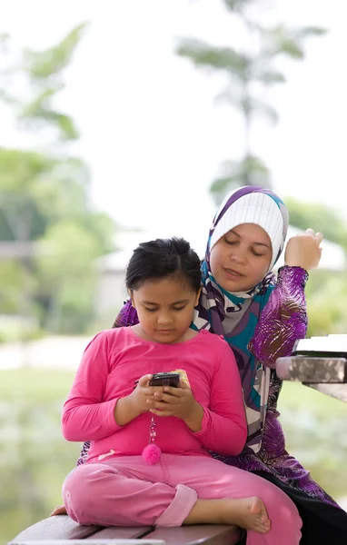 Мама и дочь играют в мобильный телефон — стоковое фото