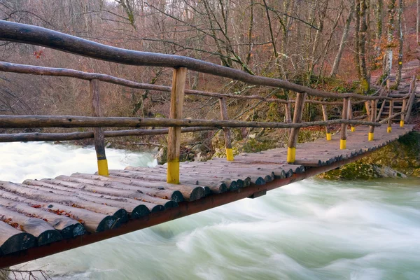 Wooden bridge over mountain river — Stock Photo, Image