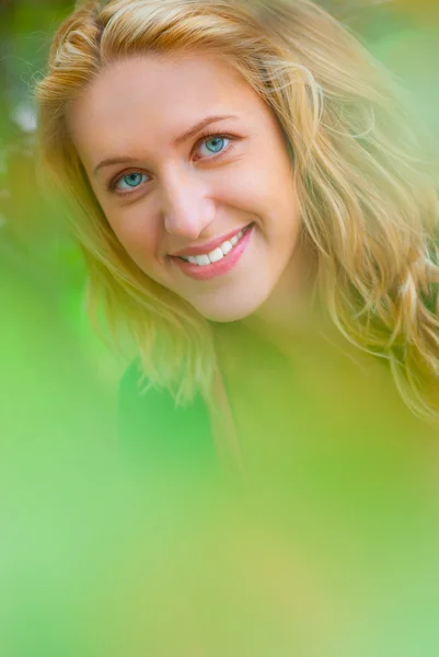 Porträtt av ung blondin genom bladverk. — Stockfoto