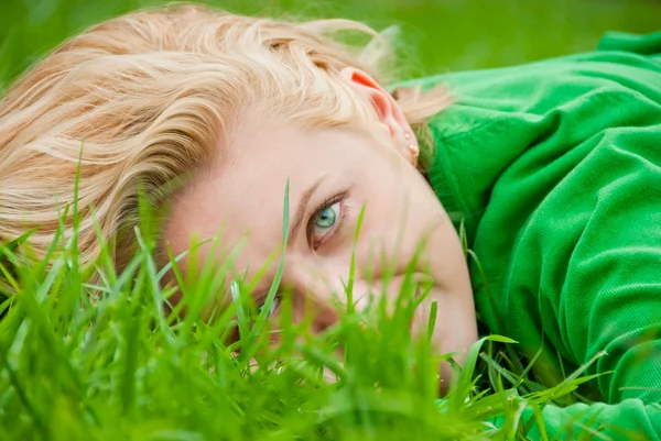 Jonge blonde liggen in een gras — Stockfoto