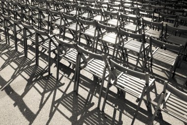 Lots of wooden chairs standing in a row. Monochrome image. clipart