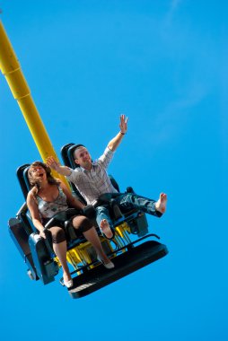 Happy young couple riding on the attraction clipart