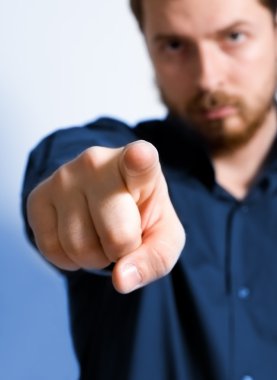 Serious adult man pointing towards viewer - focus on index finger clipart