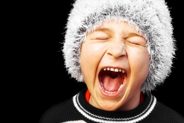 Portrait of a young boy screaming on black background clipart