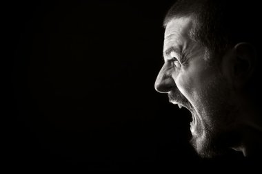 Portrait of screaming angry man on black background clipart