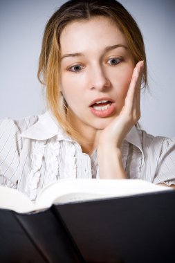 Portrait of young woman amazed by what she is reading clipart