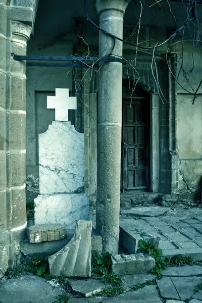 Stock image Halloween: broken creepy tombstone in front of abandoned building