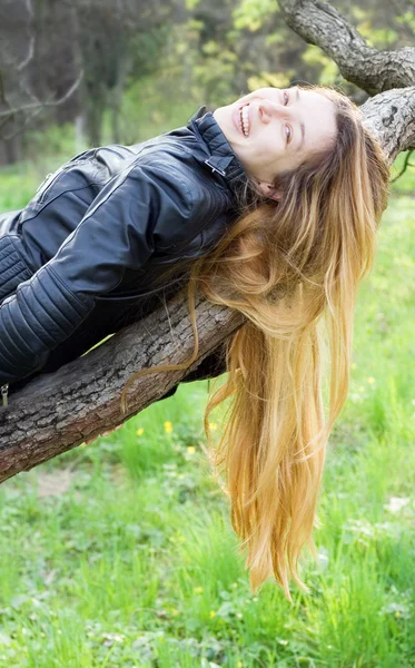 Mooi meisje lachen, op een boomtak — Stockfoto