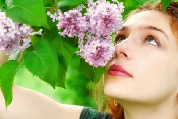 Jovem mulher cheirando flores lilás — Fotografia de Stock