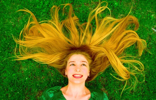 Girl with beautiful hair laying in the grass — Stock Photo, Image