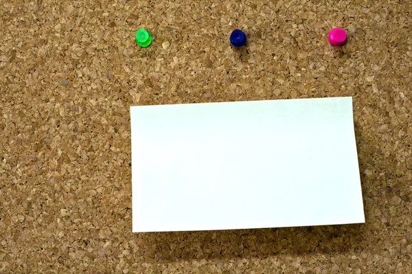Blank reminder on wooden board and three colorful pins
