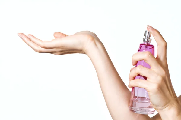 Жінка руки з рожевою пляшкою парфумів — стокове фото