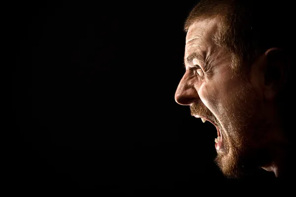 Wut-Konzept - Mann schreit vor schwarzem Hintergrund Stockbild
