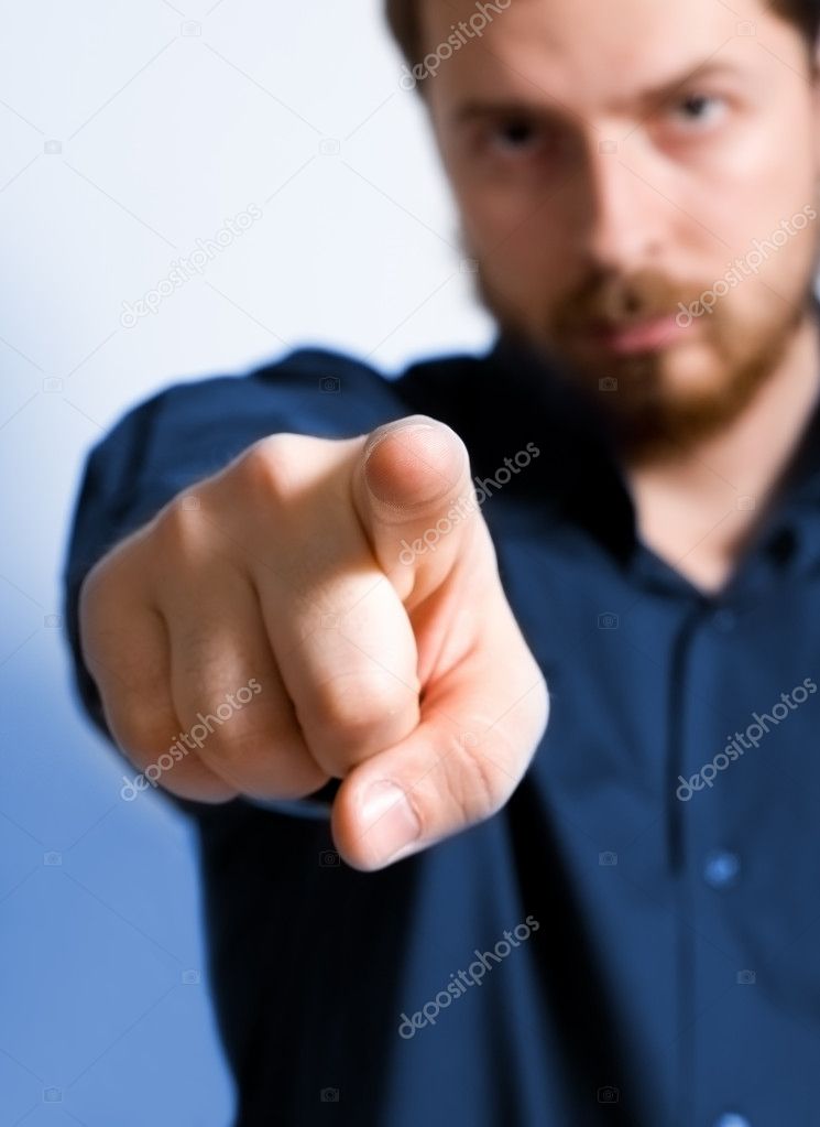 Serious adult man pointing towards viewer - focus on index finger