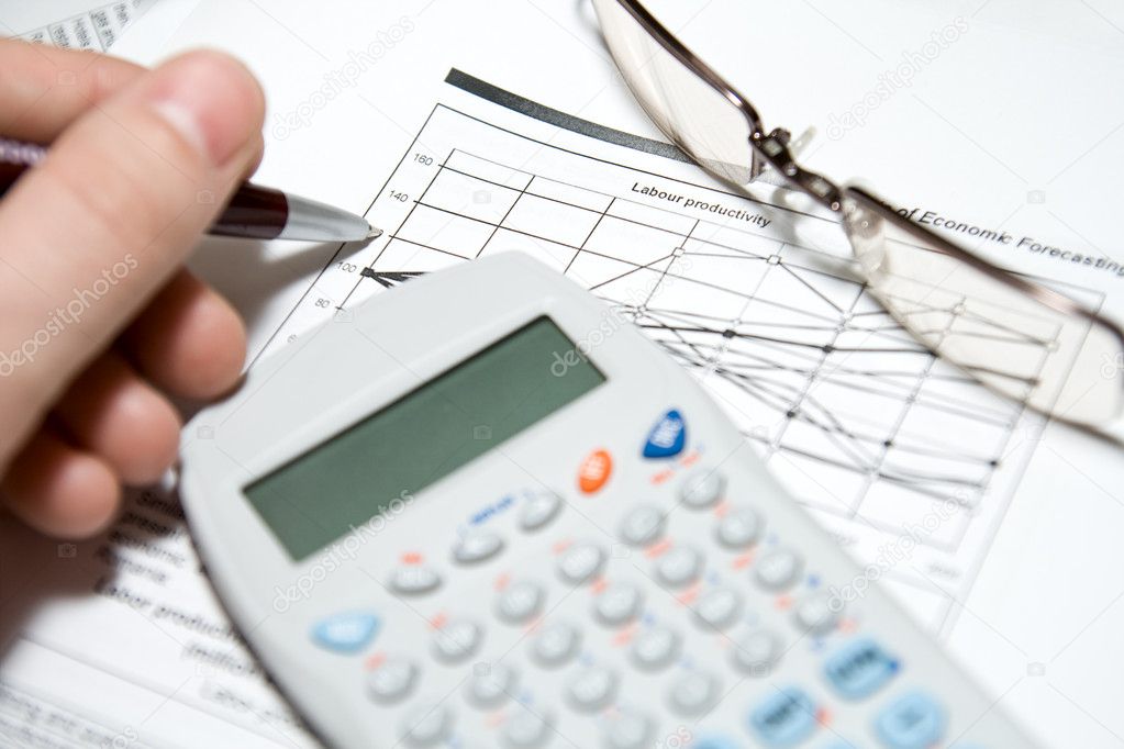 Financial analysis: hand with pen, calculator, glasses and charts