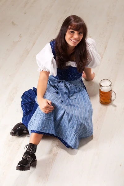 Sitting bavarian girl in a costume with a beer mug — Stock Photo, Image
