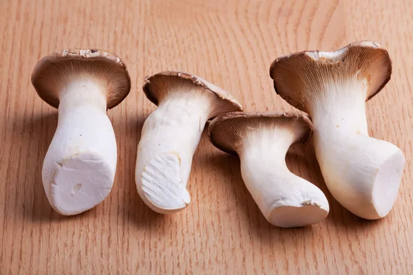 stock image Four king oyster mushrooms on a wooden table