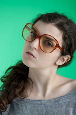 yeşil bir arka plan üzerinde büyük gözlüklü kız