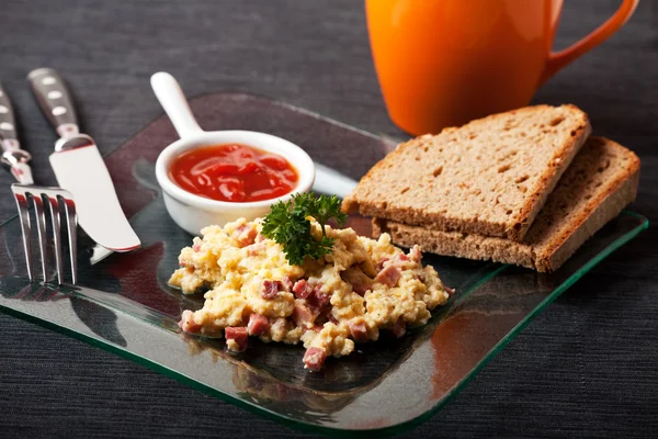 Scambled eggs with ham cubes on a glass plate — Stock Photo, Image