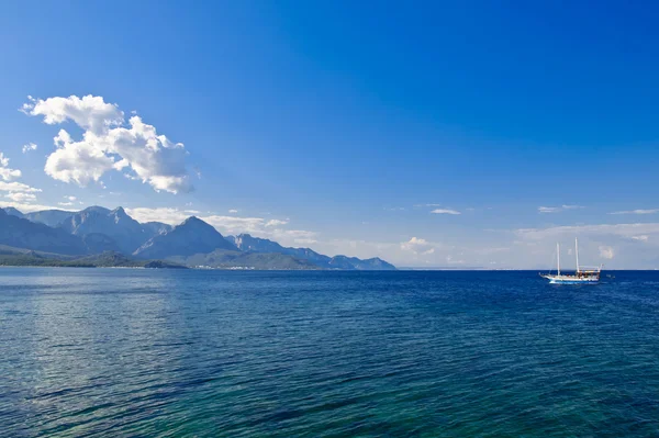 Mar, cielo, montañas y pequeño barco Fotos de stock libres de derechos