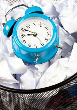 Close up of Blue alarm clock sat in a waster paper basket clipart