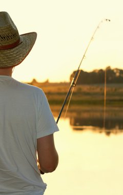 The fisherman stand on river bank and fishes. clipart